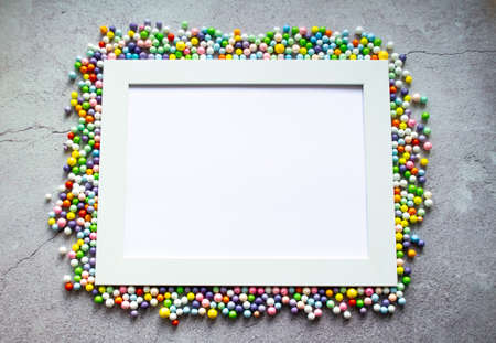 White frame with multicolored small balls around. Against the background of cracked concrete. Copy space.の写真素材