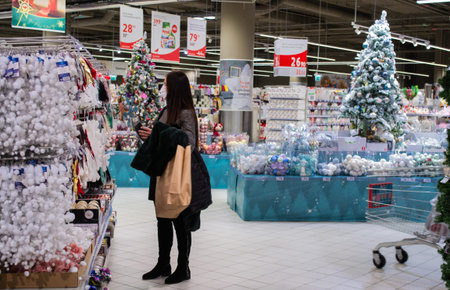 Moscow, Russia, November 2020: a young masked woman looks at and selects Christmas toys at a...