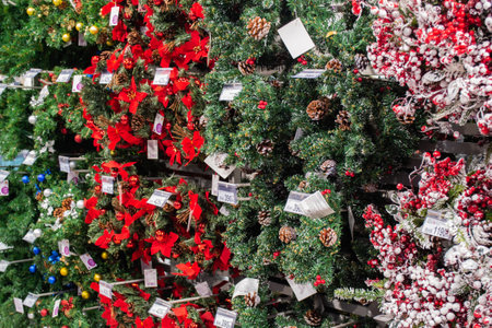 Moscow, Russia, November 2020: a Large number of Christmas tree wreaths with decorations made of baubles, red bows, pine cones and artificial berries with snow.のeditorial素材