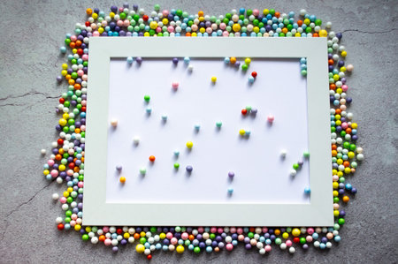 White frame with multicolored small balls around and inside. Against the background of cracked...