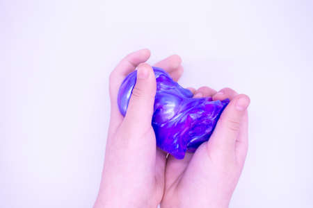 Close up of game with two-color blue and pink slime in a hand on whiteの写真素材