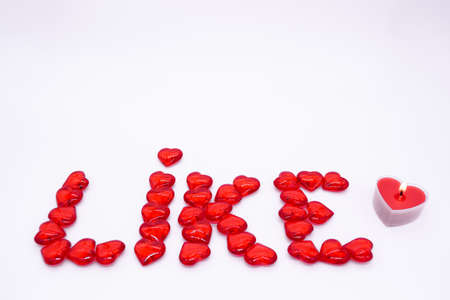 The word LIKE is laid out with red glass hearts on  whiteの写真素材