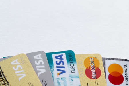 Moscow, Russia, August 2019: Credit cards: Visa, Visa gold, Visa electron, Mastercard, Mastercard gold. Cards with logos are laid out at the bottom of the frame. Copy space on the top.のeditorial素材