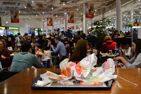 Moscow, Russia, November 2019: Close-up of a tray with leftover food, paper packaging from hamburgers on a blurry background of people eating on a food court in a shopping center.のeditorial素材