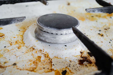 Close up of a very dirty white gas stove with yellow streaks and greasy spots.の写真素材