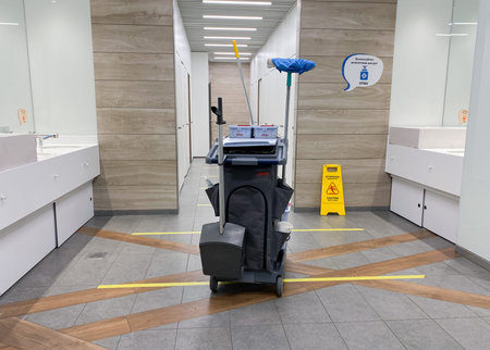MOSCOW, Russia, May 2021: A cleaning cart with mops in an empty public toilet. On the floor dividing...