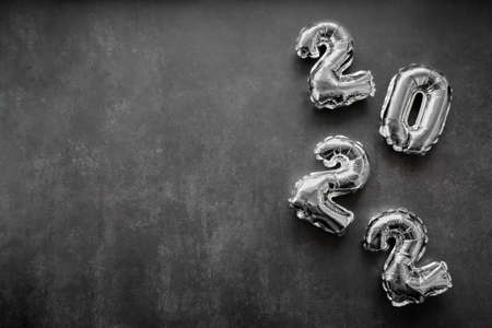 Inflatable shiny silver numbers of the new year 2022 on a dark gray or black background. Copy space.の写真素材