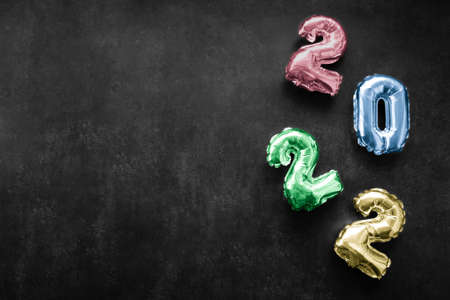 Inflatable shiny colorful numbers red, blue, green, yellow color of the new year 2022 on a dark gray or black background. Copy space.の写真素材