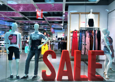 Moscow, Russia, July 2019: Showcase of clothing store with male and female mannequins and large volume red letters sale.のeditorial素材