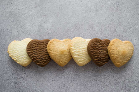 Multicolored cookies in the shape of a heart: vanilla, lemon, chocolate. Gray background, copy space.の写真素材