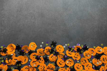 Halloween background: confetti in the shape of orange pumpkins, black spiders and stars. Gray background. Copy space.の写真素材