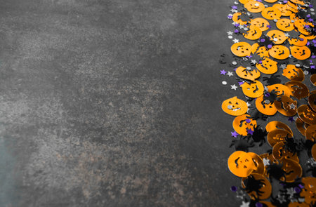 Halloween background: confetti in the shape of orange pumpkins, black spiders and stars. Gray background. Copy space.の写真素材
