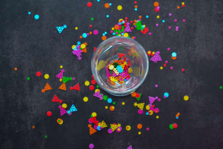 A wine glass with splashes of confetti on dark background. copyspace. Concept of party, celebration, New year, Christmas, birthdayの写真素材