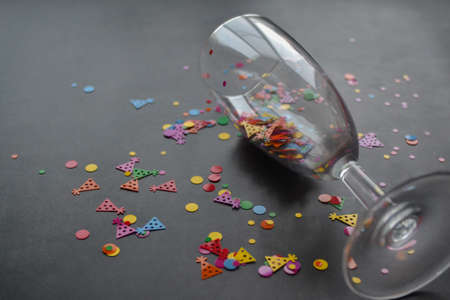 A wine glass with splashes of confetti on dark background. copyspace. Concept of party, celebration, New year, Christmas, birthdayの写真素材