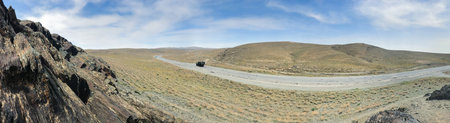 Panorama of open road. Wide view of the steppe landscape of winding road between hills, rock. blue...