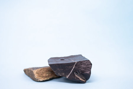 Black and brown natural stones podium on light blue background, platform for product display. Blank...