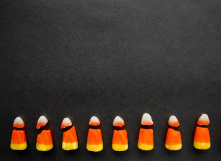 Broken candy corn look like small bad teeth. Black background. copyspace. Halloween harmful sweets concept.の写真素材