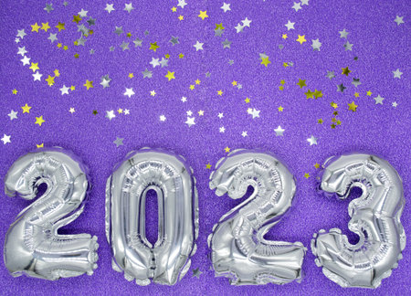 Inflatable shiny silver numbers of the New year 2023 on purple, very pericolor background with shiny...