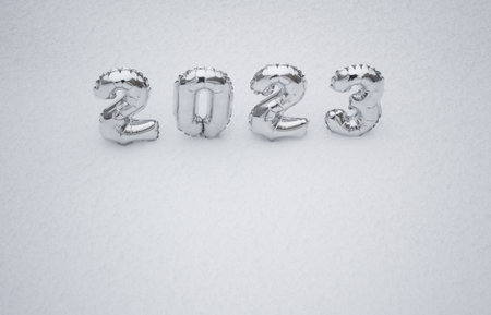 Silver numbers of the New Year 2023, in winter on a background of white snow with copy space.