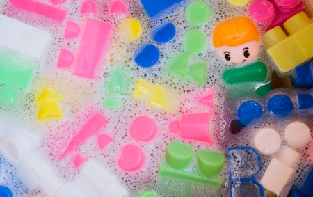 Washing of children toys, plastic building blocks with figurines. A smiling little fellow and colorful cubes float in the foaming water. The concept of hygiene, cleanliness. safety and disinfection.の写真素材