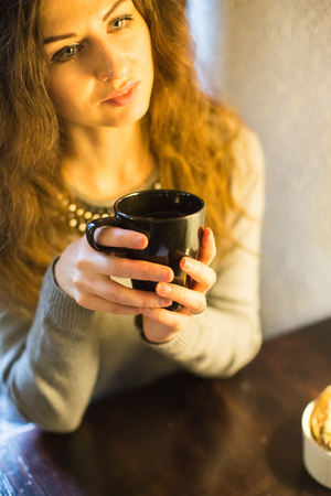 Girl drinking hot tea at a table in a cafeの写真素材