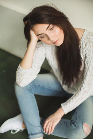 Portrait of young lady sitting on chair in photostudio interiorの写真素材