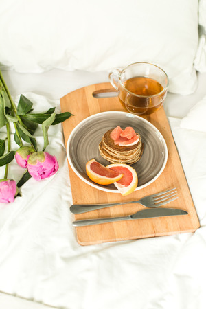 Breakfast in bed, Oatmeal pancakes with grapefruit, tea and Peoniesの写真素材