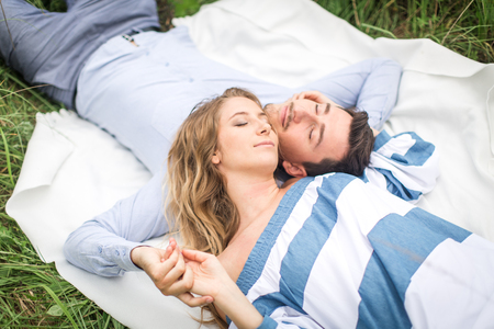 young couple man and woman lie on the rug on natureの写真素材