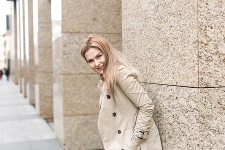 young woman in bright coat walks in the cityの写真素材