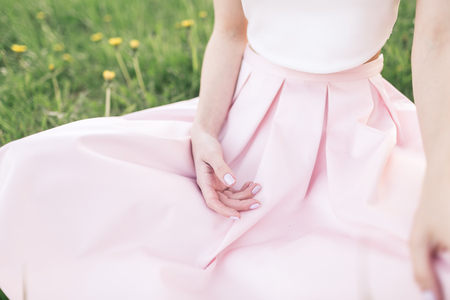 Girl in pink dress sits on the grassの写真素材