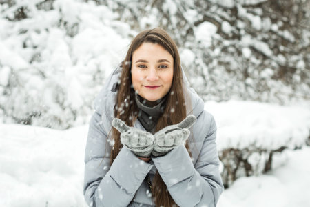 Young woman winter portrait. Winter woman Blowing Snowの写真素材