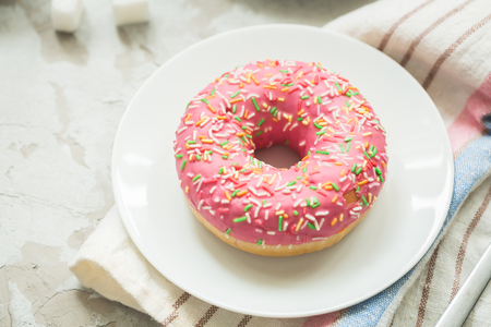 Donut with pink frosting on plateの写真素材