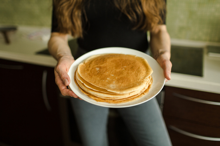 the girl is standing with pancakes in the kitchenの写真素材