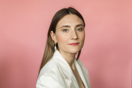 portrait of a beautiful woman in a white jacket on a pink background