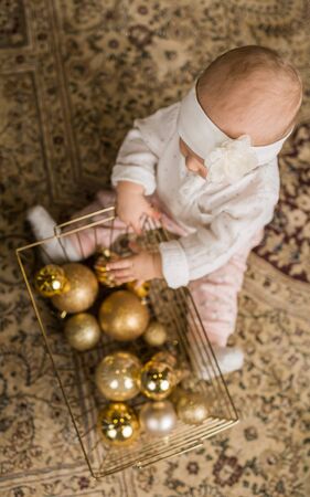 little girl plays with a basket of Christmas toysの写真素材