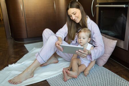mother and daughter chat with relatives online on a tablet. concept video communication quarantined 2020の写真素材