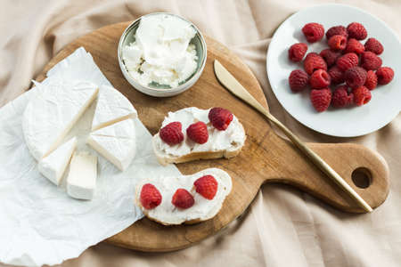 aesthetic breakfast camembert, cream cheese and raspberries on a wooden boardの写真素材