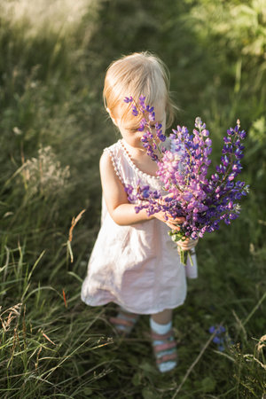 little girl walking with a bouquet of flowersの写真素材