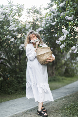 pregnant girl in the lilac garden with basketの写真素材