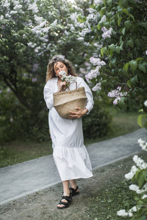 pregnant girl in the lilac garden with basketの写真素材