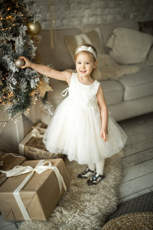 little girl rejoices in the christmas. on the background of an elegant Christmas treeの写真素材