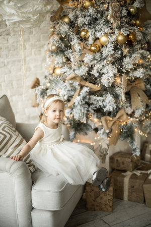 little girl rejoices in the christmas. on the background of an elegant Christmas treeの写真素材