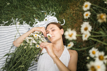 young woman lies in daisies, in a field of daisiesの写真素材