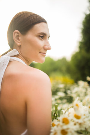 young woman with a large bouquet of daisies sits in natureの写真素材