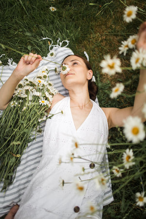 young woman lies in daisies, in a field of daisiesの写真素材