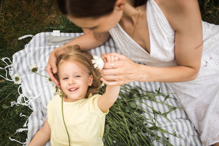 mother plays with her daughter, relax, collect a bouquet of daisiesの写真素材