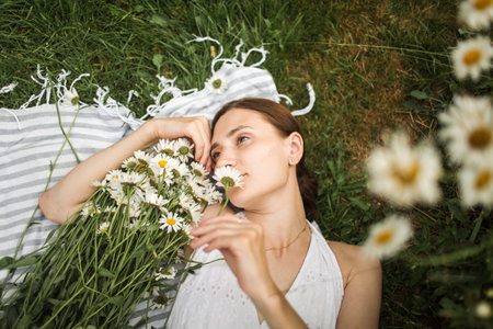 young woman lies in daisies, in a field of daisiesの写真素材