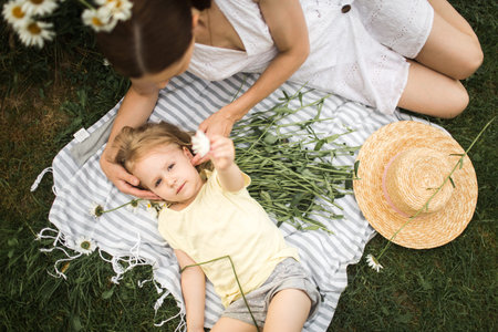mother plays with her daughter, relax, collect a bouquet of daisies