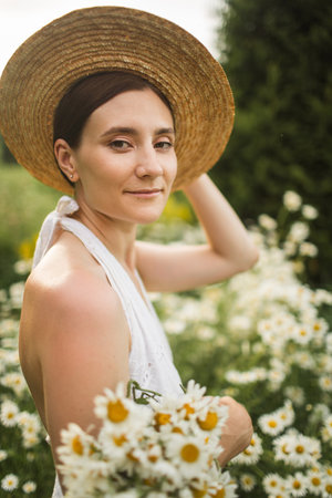beautiful girl in a hat with a large bouquet of daisiesの写真素材