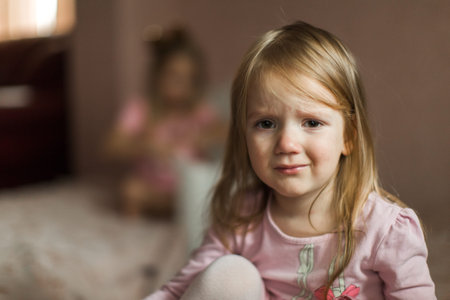little sisters quarreled and sit apart on different beds